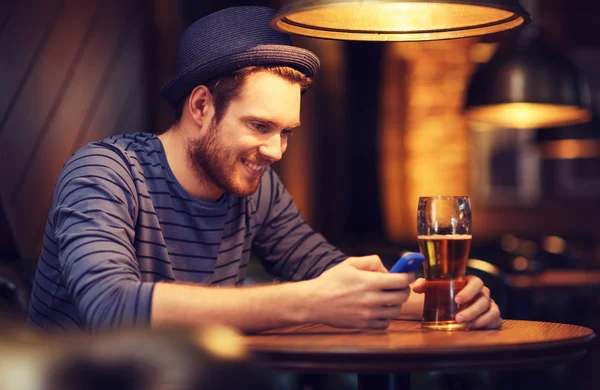 Man met smartphone en bier texting op bar — Stockfoto