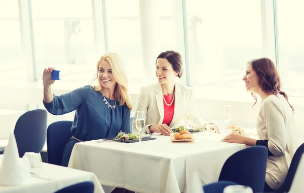 Kvinnor med smartphone med selfie på restaurang — Stockfoto