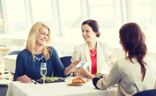 Happy women giving birthday present at restaurant — Stock Photo, Image