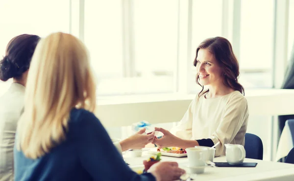 Happy women giving birthday present at restaurant — Stock Photo, Image