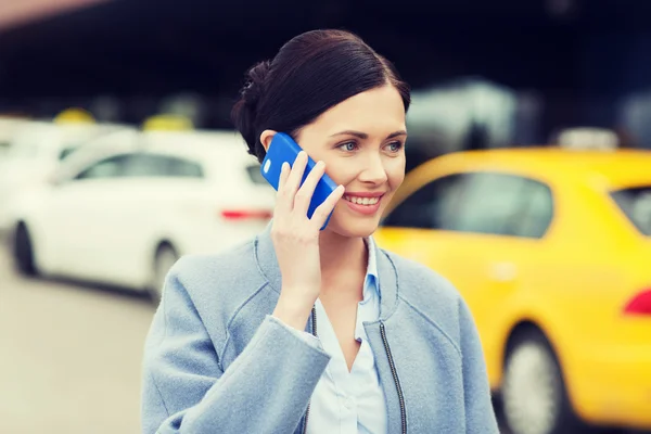 Lachende vrouw met smartphone over taxi in stad — Stockfoto