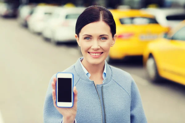 Smiling woman showing smartphone over taxi in city — Stock Photo, Image