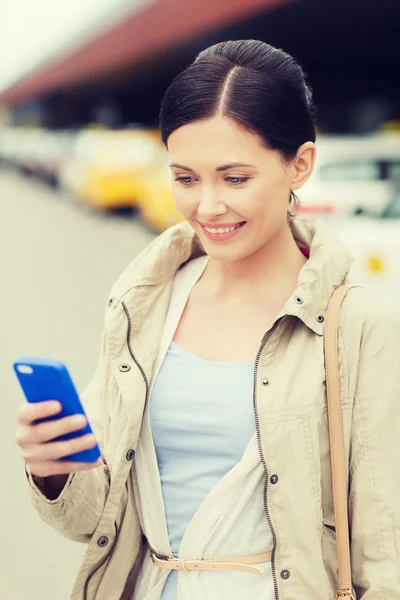 Smiling woman with smartphone over taxi in city — Stock Photo, Image