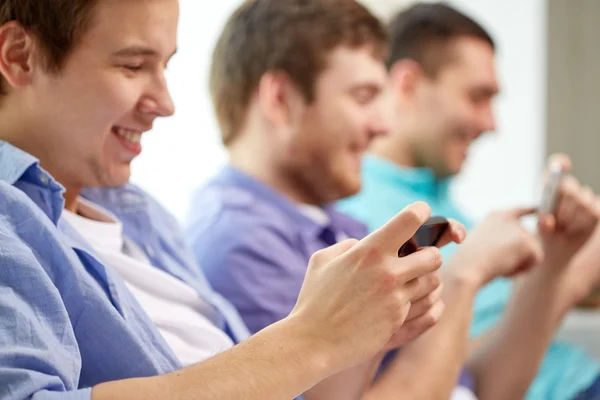 Close up of happy friends with smartphones at home — Stock Photo, Image