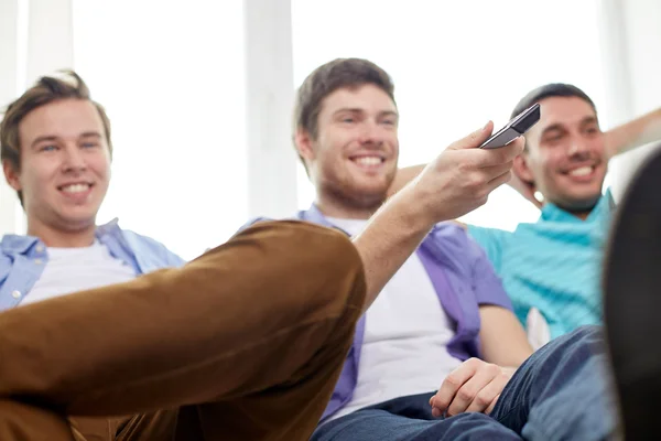 Amici maschi felici con telecomando guardando la tv a casa — Foto Stock