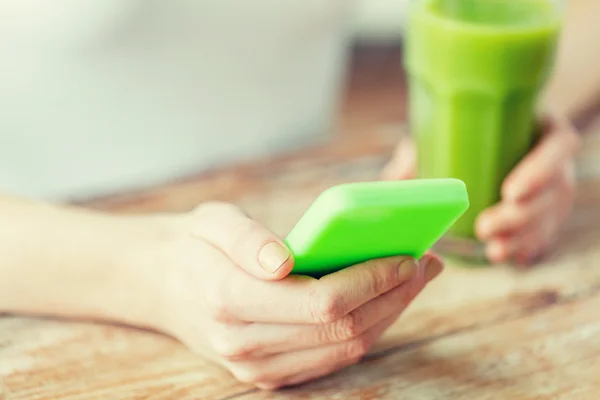 Primer plano de la mujer con teléfono inteligente y jugo verde —  Fotos de Stock