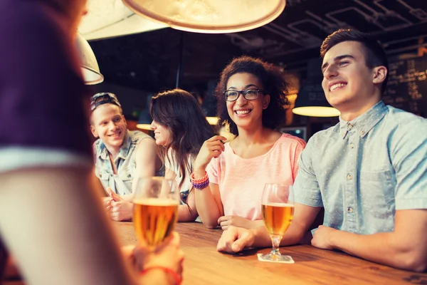 Amigos felizes bebendo cerveja e conversando no bar — Fotografia de Stock