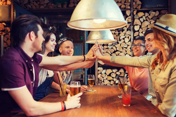 Счастливые друзья с напитками, делающими высокую пятерку в баре — стоковое фото