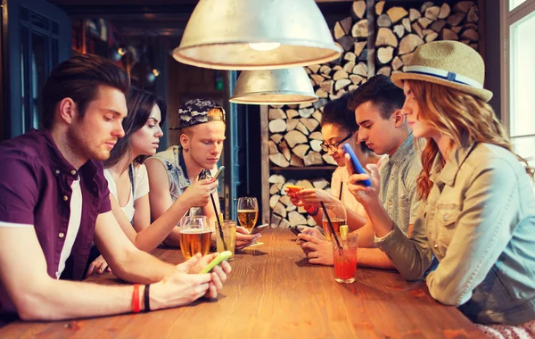 Amigos com smartphones e bebidas no bar — Fotografia de Stock