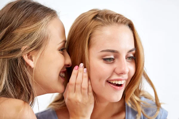 Mujeres jóvenes felices susurrando chismes en casa —  Fotos de Stock