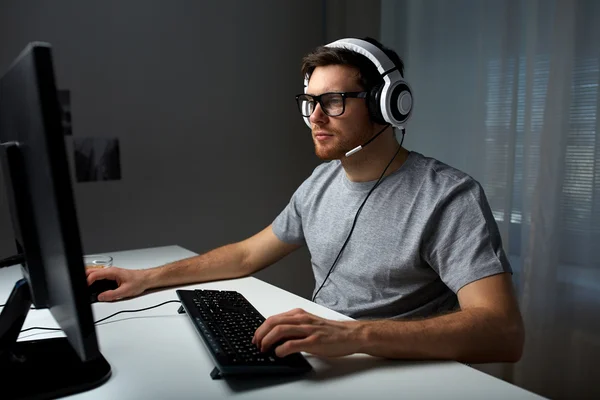 Hombre en auriculares jugando videojuego de ordenador en casa —  Fotos de Stock