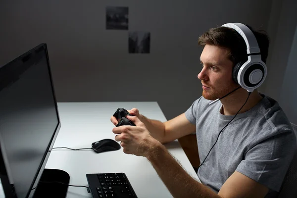 Homem em fone de ouvido jogando jogo de computador em casa — Fotografia de Stock