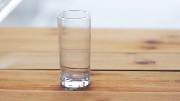 Water gieten in glas op houten tafel — Stockvideo