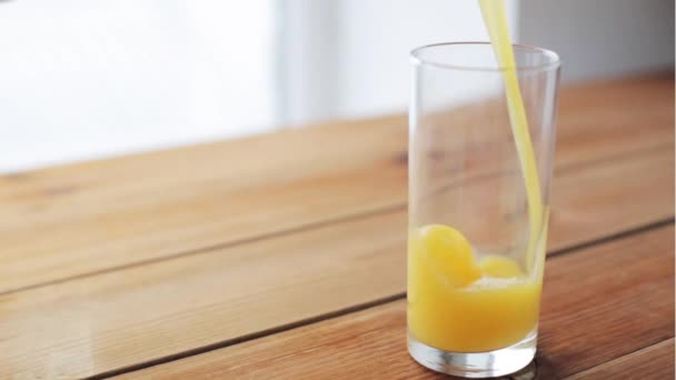 Sinaasappelsap gieten in glas op houten tafel — Stockvideo