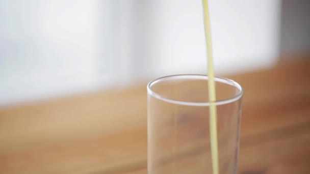 Orangensaft fließt ins Glas auf Holztisch — Stockvideo