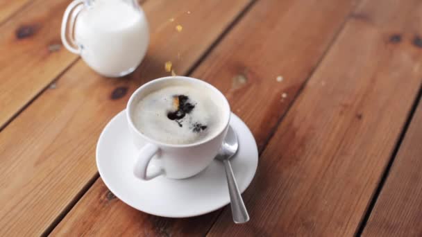 Mano dejando caer el azúcar en la taza de café en la mesa — Vídeo de stock