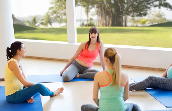 Glada gravida kvinnor sitter på mattor i gym — Stockfoto