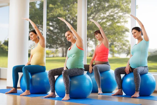 Felici donne incinte che esercitano sul fitball in palestra — Foto Stock