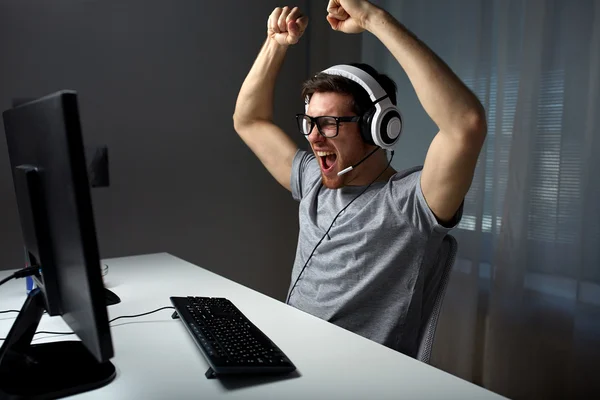 man in headset playing computer video game at home