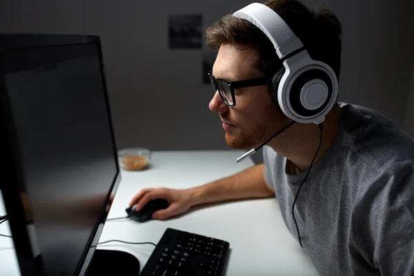 Чоловік в гарнітурі грає в комп'ютерну відеогру вдома — стокове фото