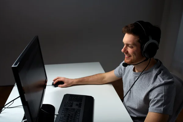 Hombre en auriculares jugando videojuego de ordenador en casa —  Fotos de Stock