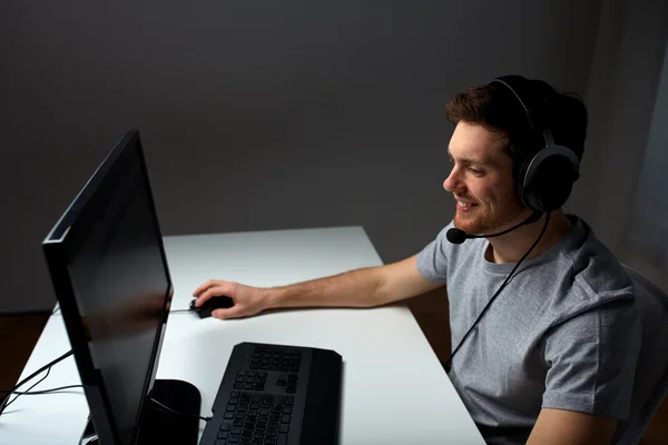 Mann mit Headset spielt Computervideospiel zu Hause Stockbild