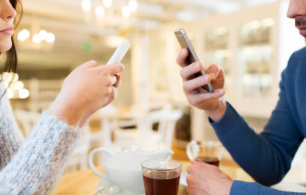 Close up of couple with smartphones at cafe — Stock Photo, Image
