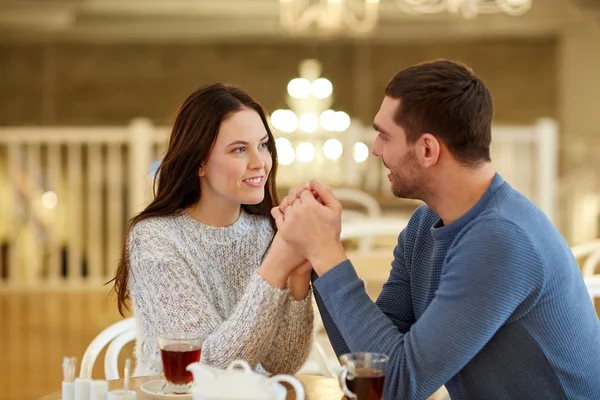 Coppia felice con tè che si tiene per mano al ristorante — Foto Stock