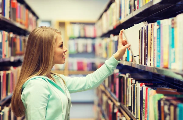 Gelukkig student meisje of vrouw met boek in bibliotheek — Stockfoto