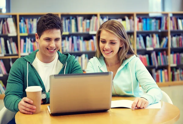 Zadowoleni uczniowie z laptopa w bibliotece — Zdjęcie stockowe