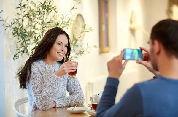 男人在咖啡店用智能手机给女人拍照 — 图库照片