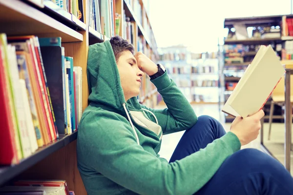 Studente ragazzo o giovane lettura libro in biblioteca — Foto Stock