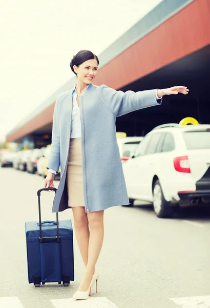 Smilende ung dame med reisepose som får drosje – stockfoto