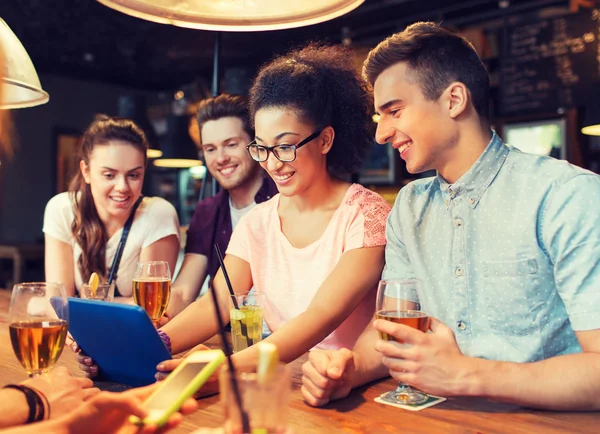 Gelukkige vrienden met tablet pc en drankjes in bar — Stockfoto