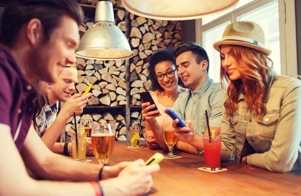 Amis heureux avec smartphones et boissons au bar — Photo