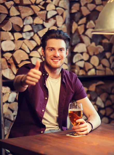 Счастливый мужчина с пивом, показывающий большие пальцы в баре — стоковое фото