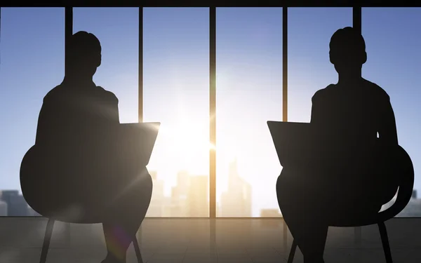 Silhouette of two business women with laptop — Stok fotoğraf