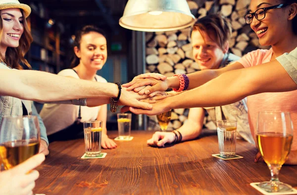 Amigos colocando as mãos em cima uns dos outros no bar — Fotografia de Stock