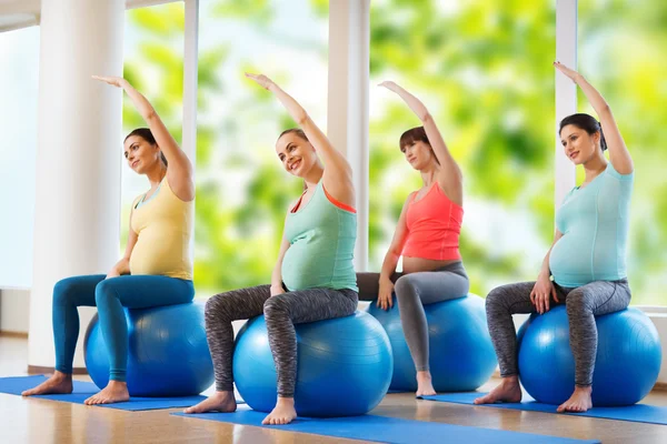 Felici donne incinte che esercitano sul fitball in palestra — Foto Stock