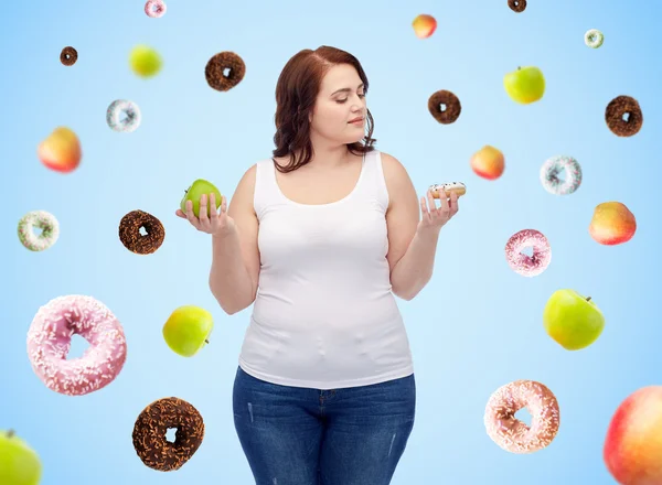 Young plus size woman choosing apple or donut Stock Picture