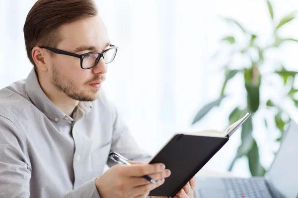 Kreativa manlig arbetstagare med bok på hemmakontoret — Stockfoto