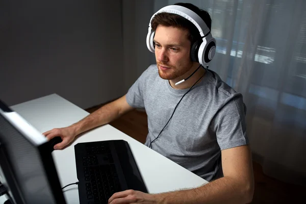 Homem em fone de ouvido jogando jogo de computador em casa — Fotografia de Stock