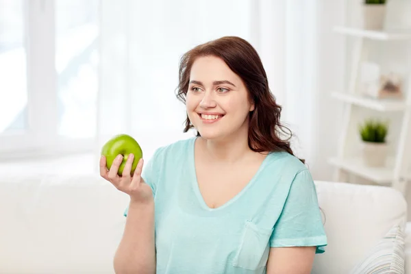 Feliz plus size mulher comer maçã verde em casa — Fotografia de Stock