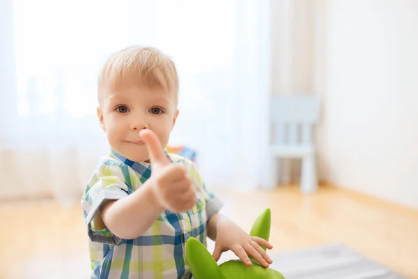 Щасливий хлопчик грає з іграшкою, показуючи великі пальці вгору — стокове фото