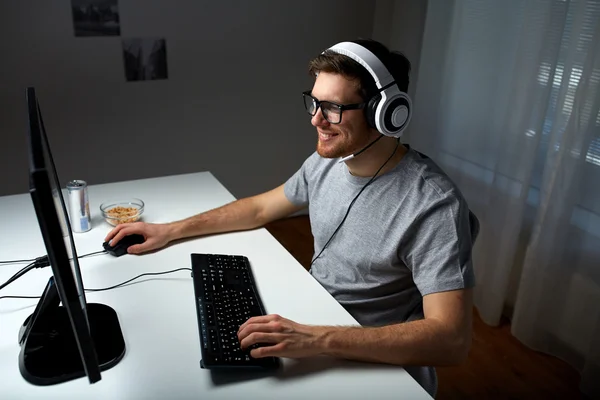 Mannen i headsetet spelar datorspel hemma Royaltyfria Stockfoton