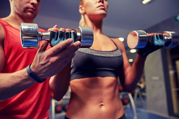 Jeune couple avec haltère flexion des muscles dans la salle de gym — Photo