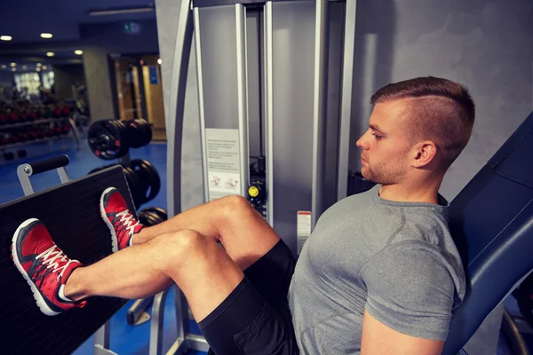 Hombre flexionar los músculos de las piernas en la máquina de gimnasio — Foto de Stock