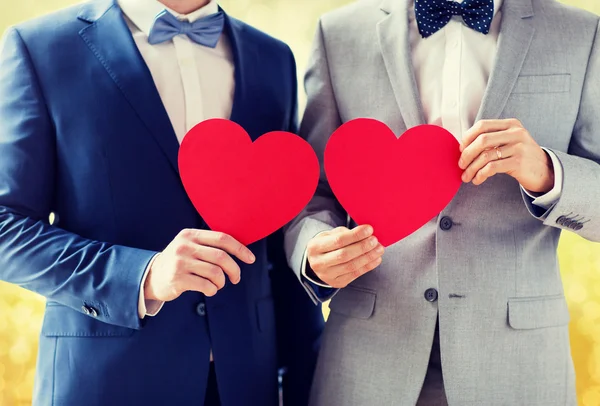 Close up of male gay couple holding red hearts — Stock Photo, Image