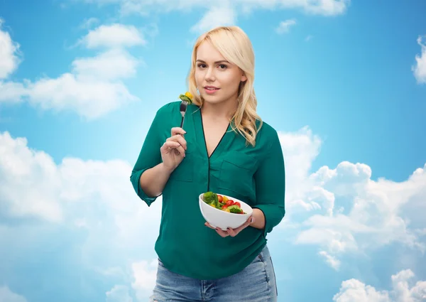 Улыбающаяся молодая женщина ест овощной салат — стоковое фото