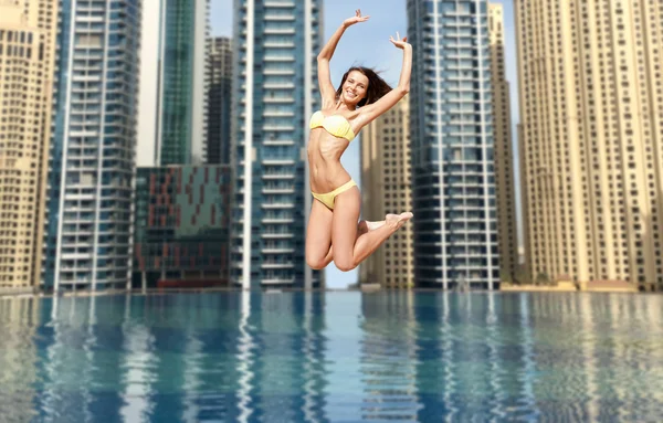 Lycklig ung kvinna hoppar över Dubai City pool — Stockfoto